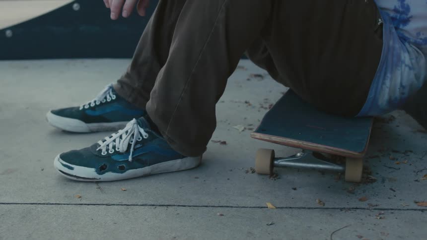 A person is sitting on his skateboard in the park