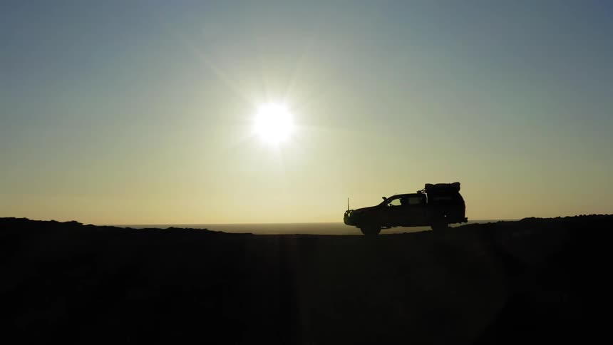 A car is driving in a rural area at dusk