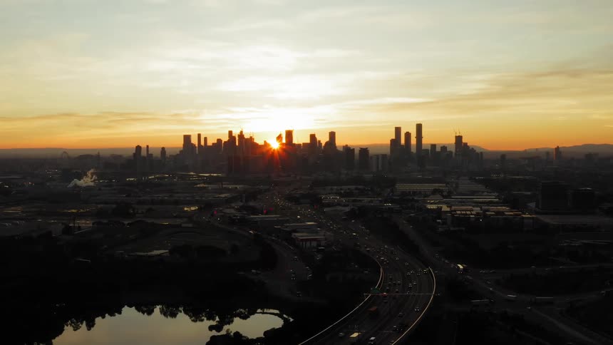 The sun peeks out from behind the city skyline
