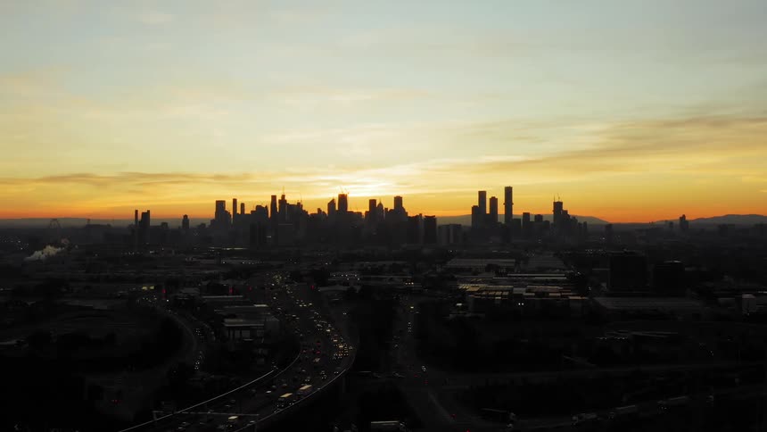 Aerial view of a vehicles driving with a city skyline in the distance