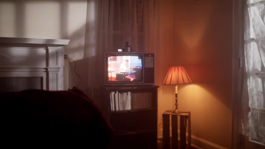 Retro tube tv on small bookshelf in dimly lit room