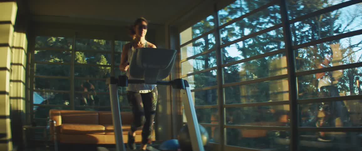 Woman with leggings and a tank top runs on the treadmill