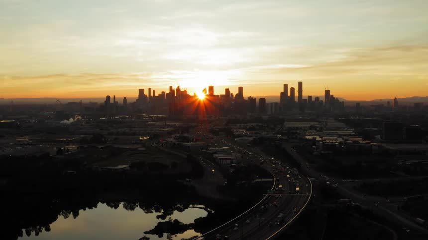 The sun disappears behind the silhouetted city skyline