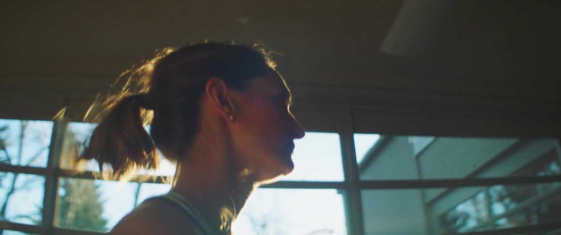 A woman checks her watch as she jogs on a treadmill at home