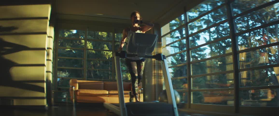 A woman is jogging next to a window at dusk
