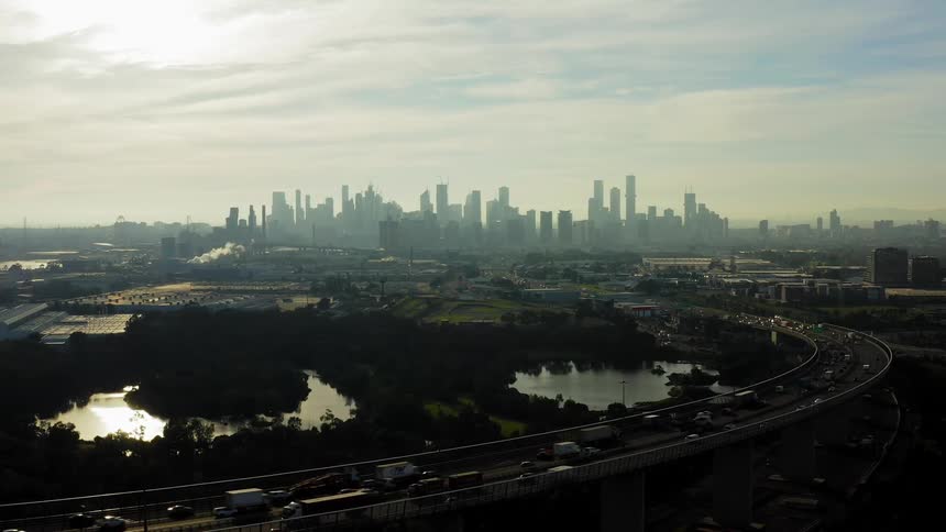 An aerial view of a city skyline with cars and truck driving on a highway