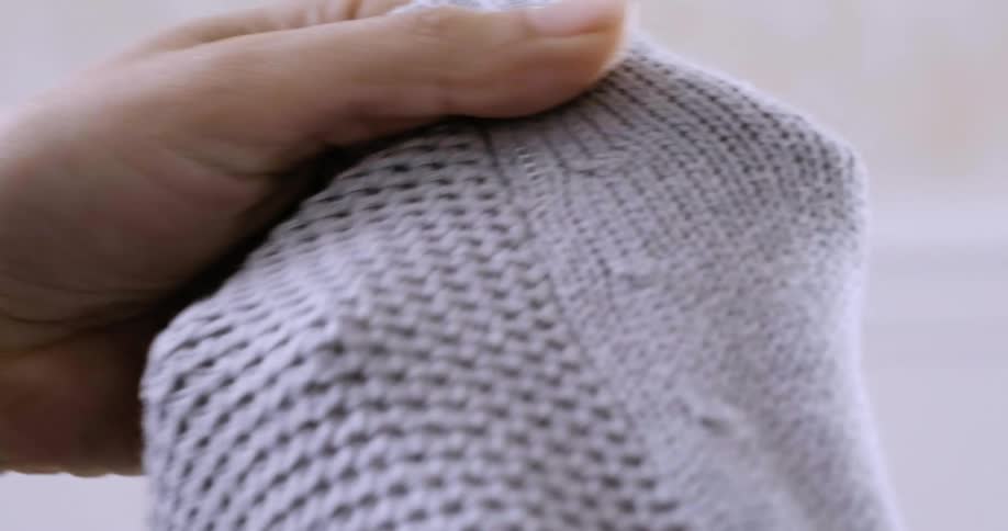 A woman runs knitted material through her hands