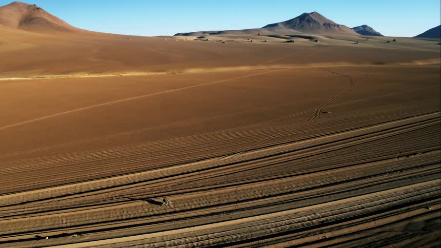 A person driving a motorcycle across a desert