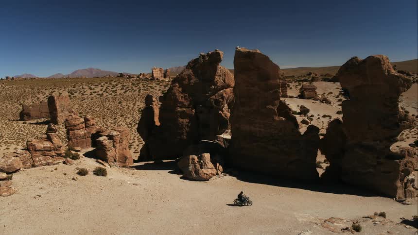 A man is riding a motorcycle through the desert