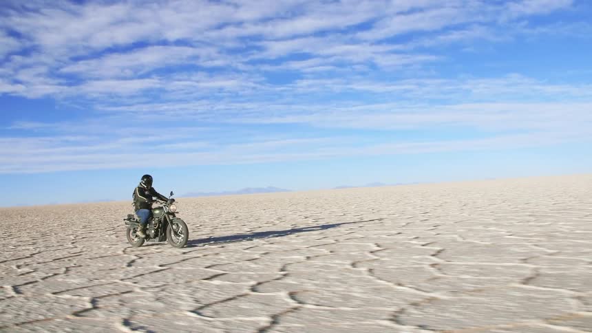 A man is riding a motorcycle through a desert