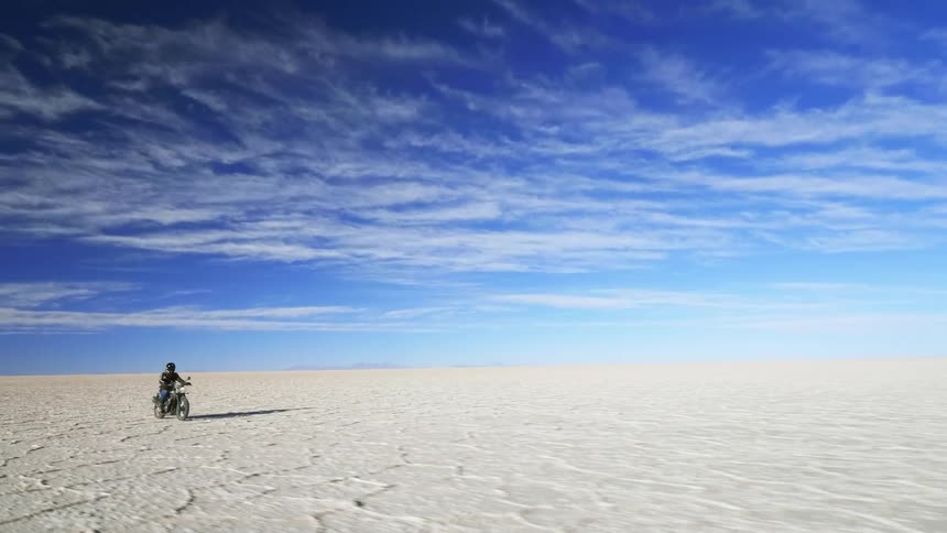 A man is riding a motorcyclethrough the desert