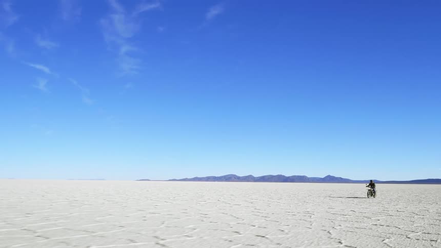 A man is riding a motorcycle through a desert