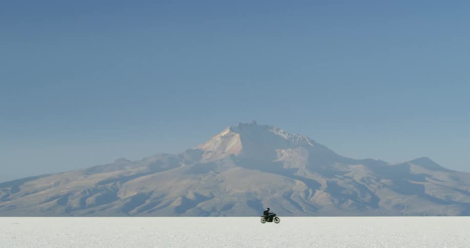 A guy is driving a motorcycle near a mountain