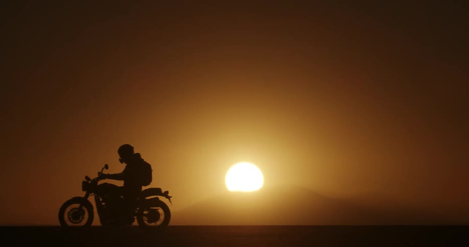 A man is riding a motorcycle at dusk