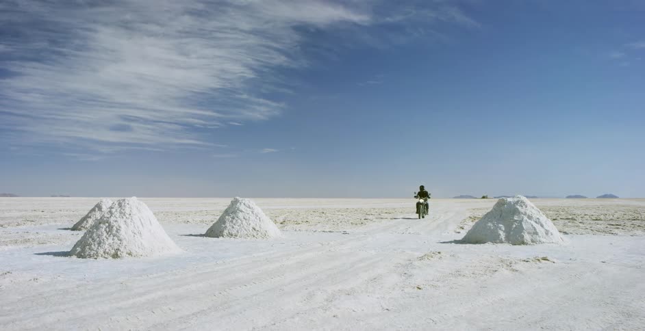 A person rides a motorcycle through the desert