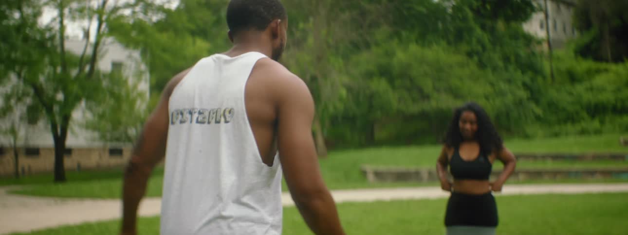 A man walks over to three women in an open yard as their athletic coach