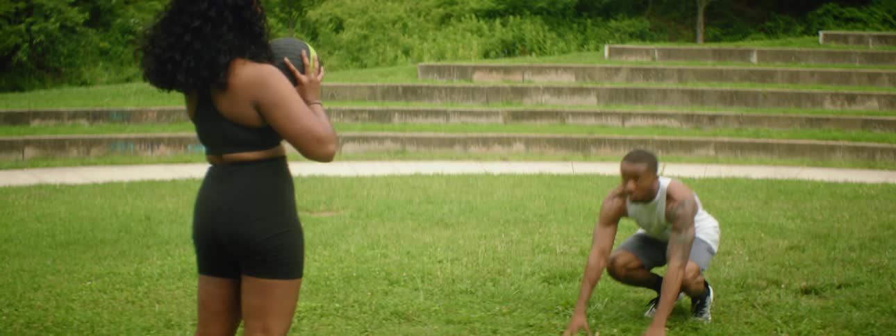 A man and woman exercise together outside and then high five one another