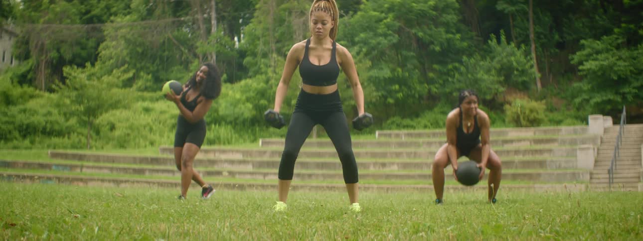 Three women work out on the grass