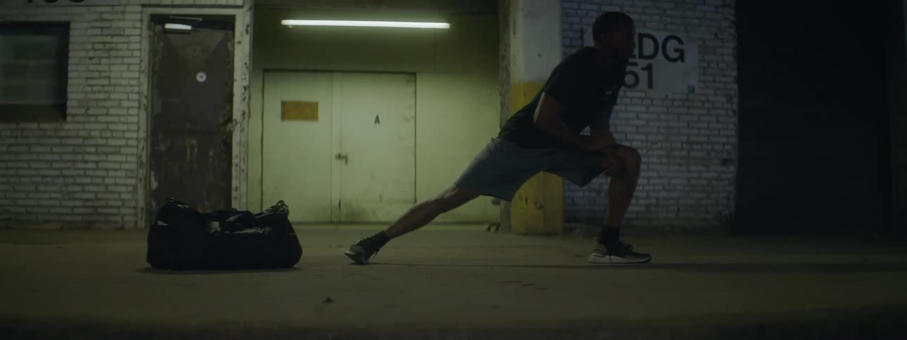 A man is exercising next to a building at night