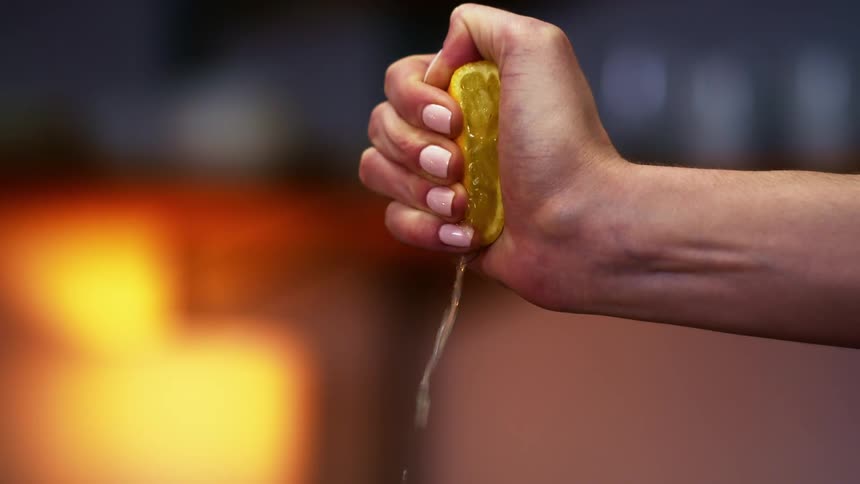 Womans hand squeezes half lemon