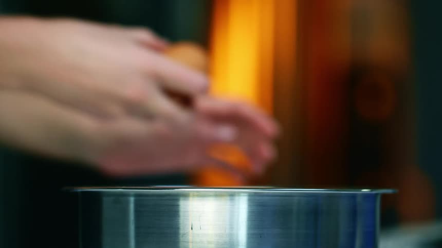 A person cracking an egg into a bowl