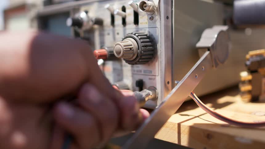 A person plugging in a wire into a machine on a table