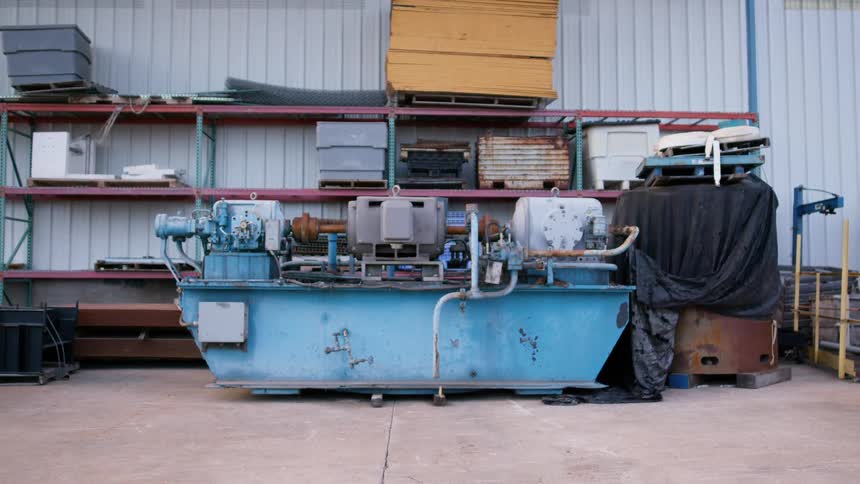Large piece of machinery resting on the floor of a warehouse in front of shelving