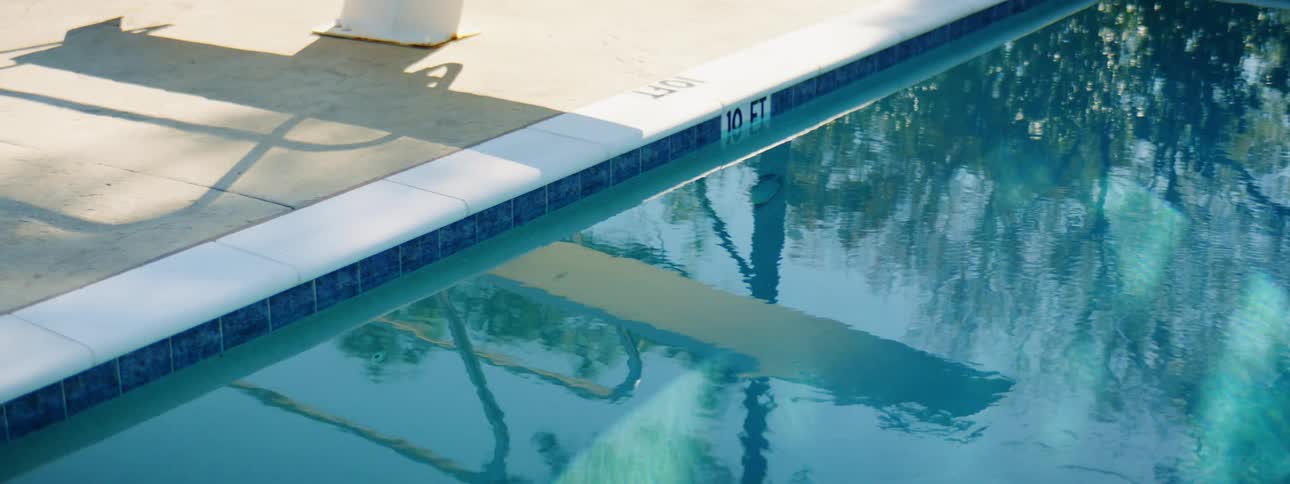 The diving board reflects off the pool water