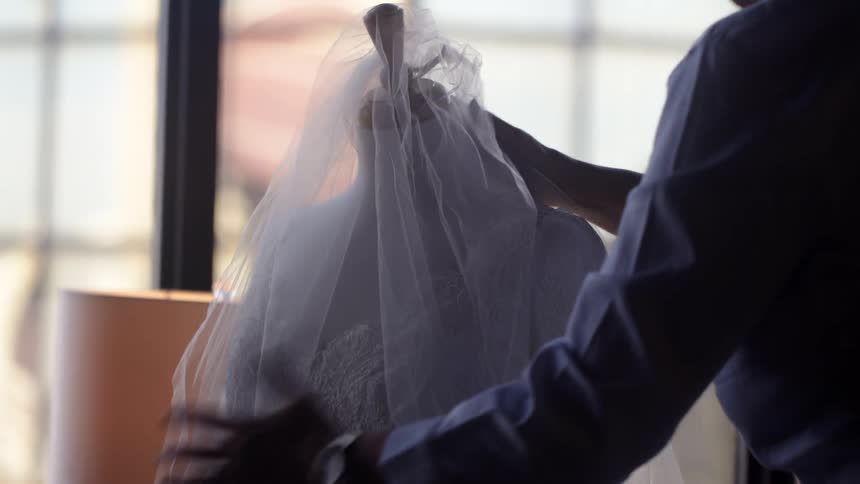 A woman is setting a wedding dress on the mannequin