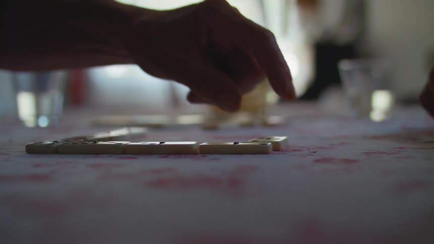 A person places a domino on the table