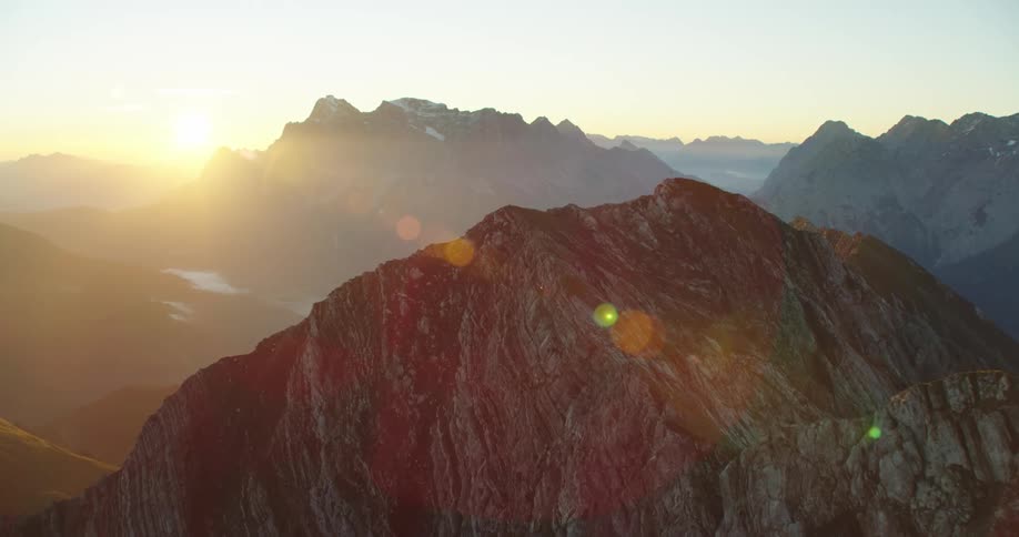 The low sun shines onto a the summit of stone mountain range