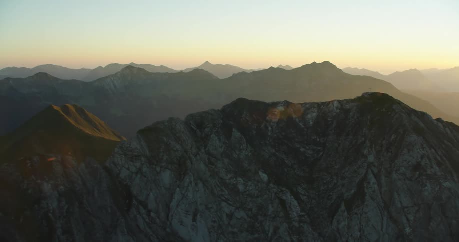 Sky over horizon and fog occupying valleys between mountains in mountain range are tinted red