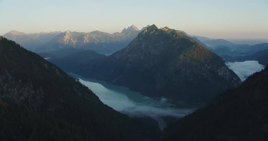 A mountain range with trees with the sky and clouds in the background