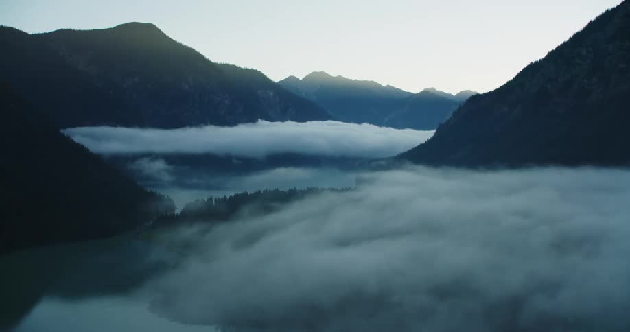 A river through a fog shrouded mountain valley during the day