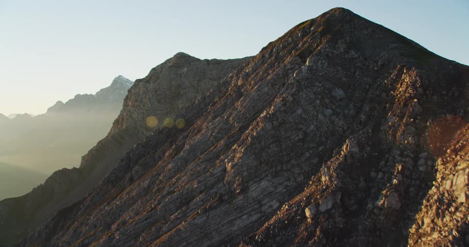 A stone mountain ridge with sparse vegetation under a clear daytime sky