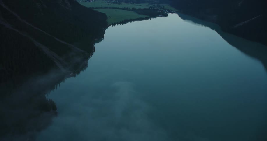 An aerial view of a calm reflective lake surrounded by mountains in nature