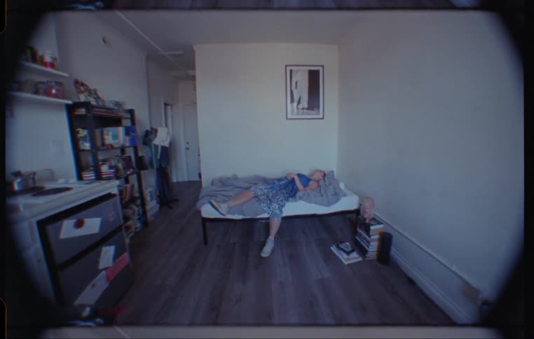 A woman sleeps on a small bed in a tiny studio apartment