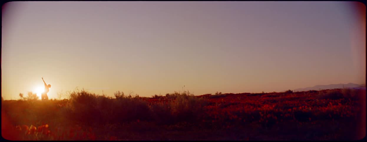 A woman dancing and running at the top of a hill