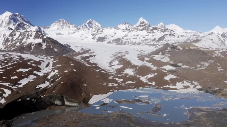 Snow coats mountain range slope bordering small lake