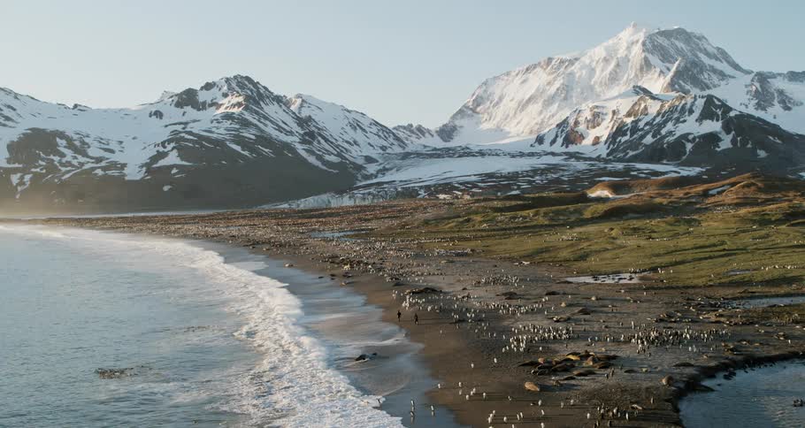 The waves crash against the shore near the mountains