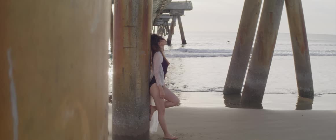 A woman is standing under the pier