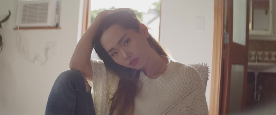 An asian female sitting in a chair playing with her hair