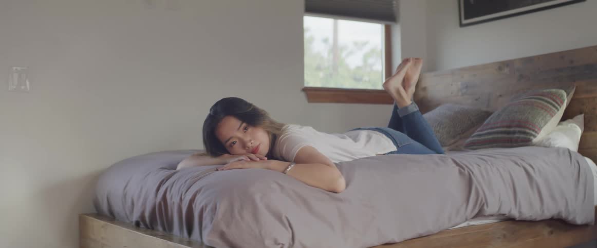 Asian woman lies face down on a bed in the bedroom