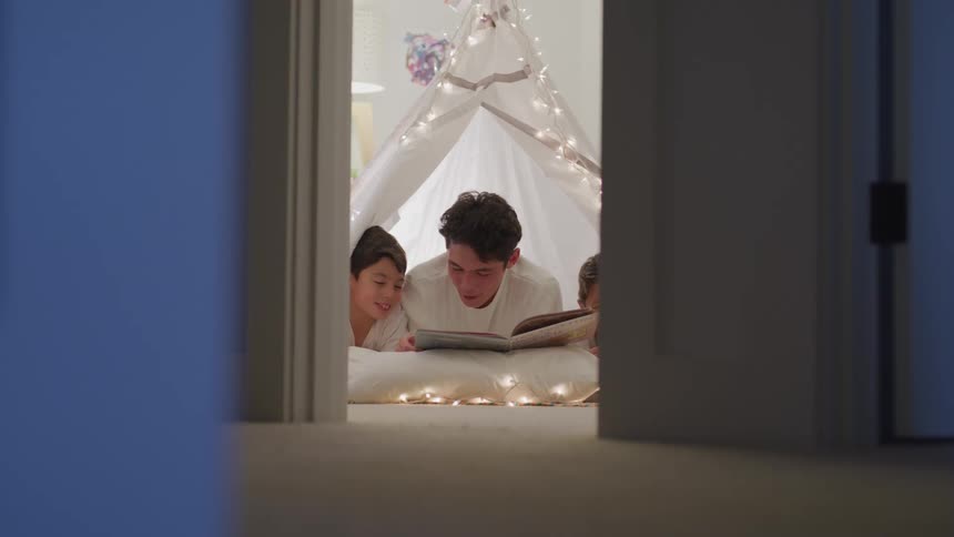A father reading to his children on the floor