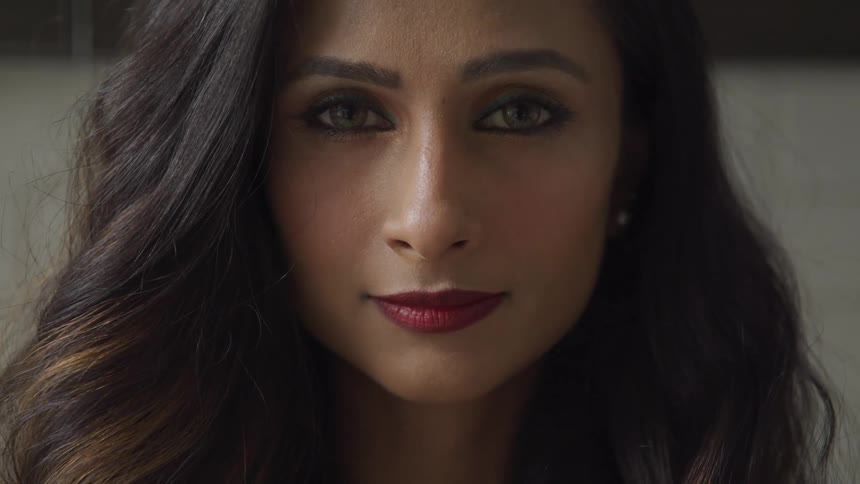 A woman with earrings lipstick and eyeshadow blinking and staring