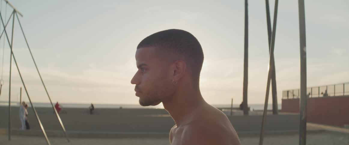 Shirtless man standing and staring while at the beach
