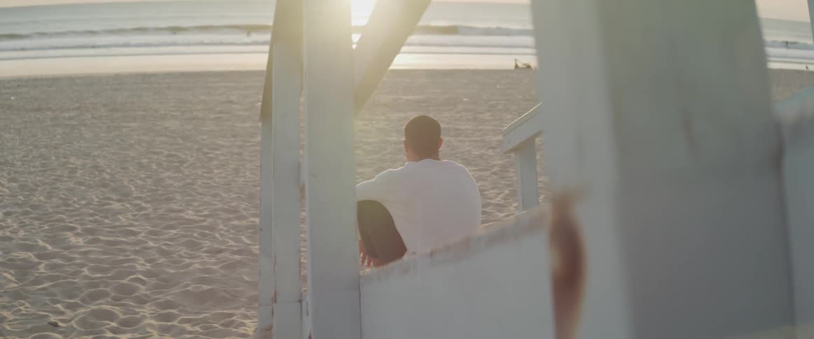 A man is sitting on a staircase at the beach