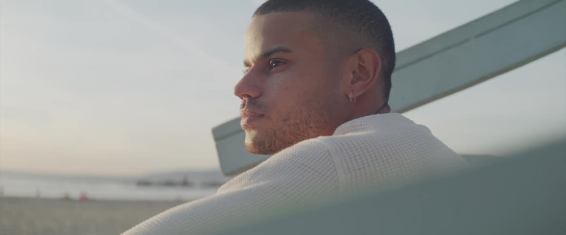 A young man sitting on the beach