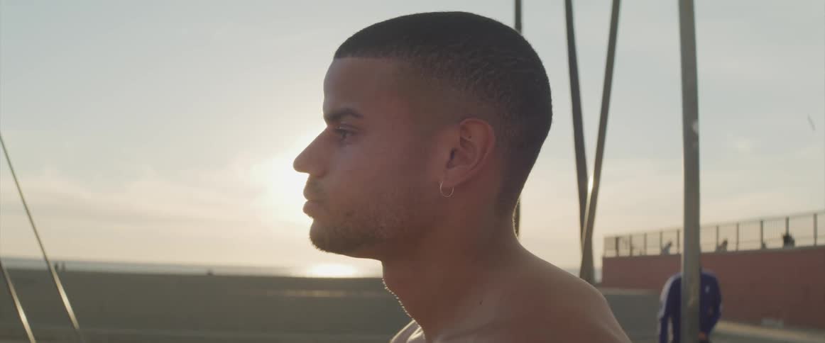 A young man standing outside looks upward as he stands in front of the sun