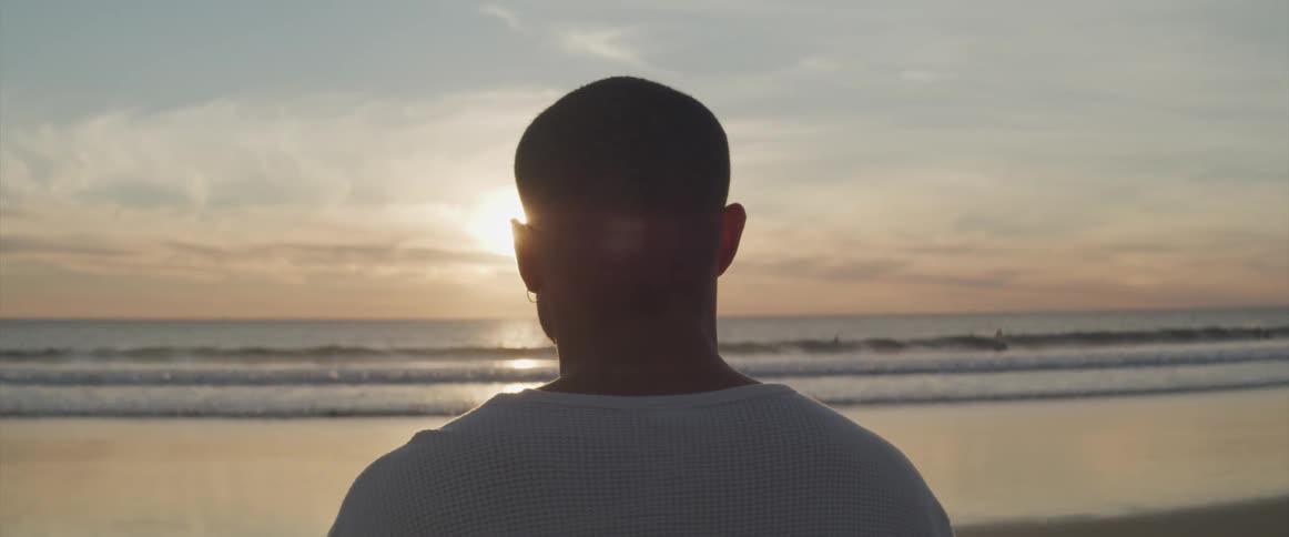 A man standing on the shore looks out at the water